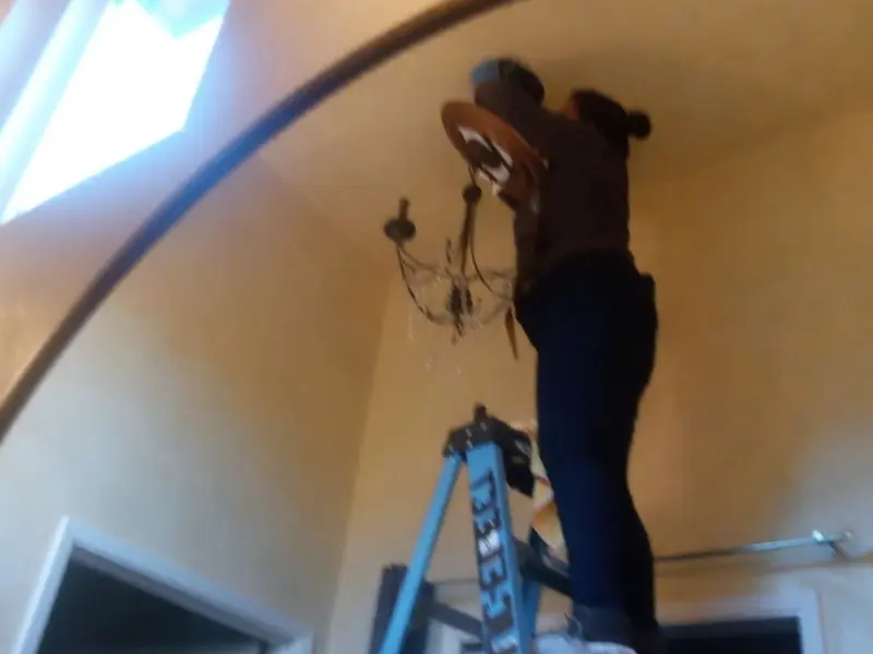 Electrician installing a chandelier in a Beaver residence